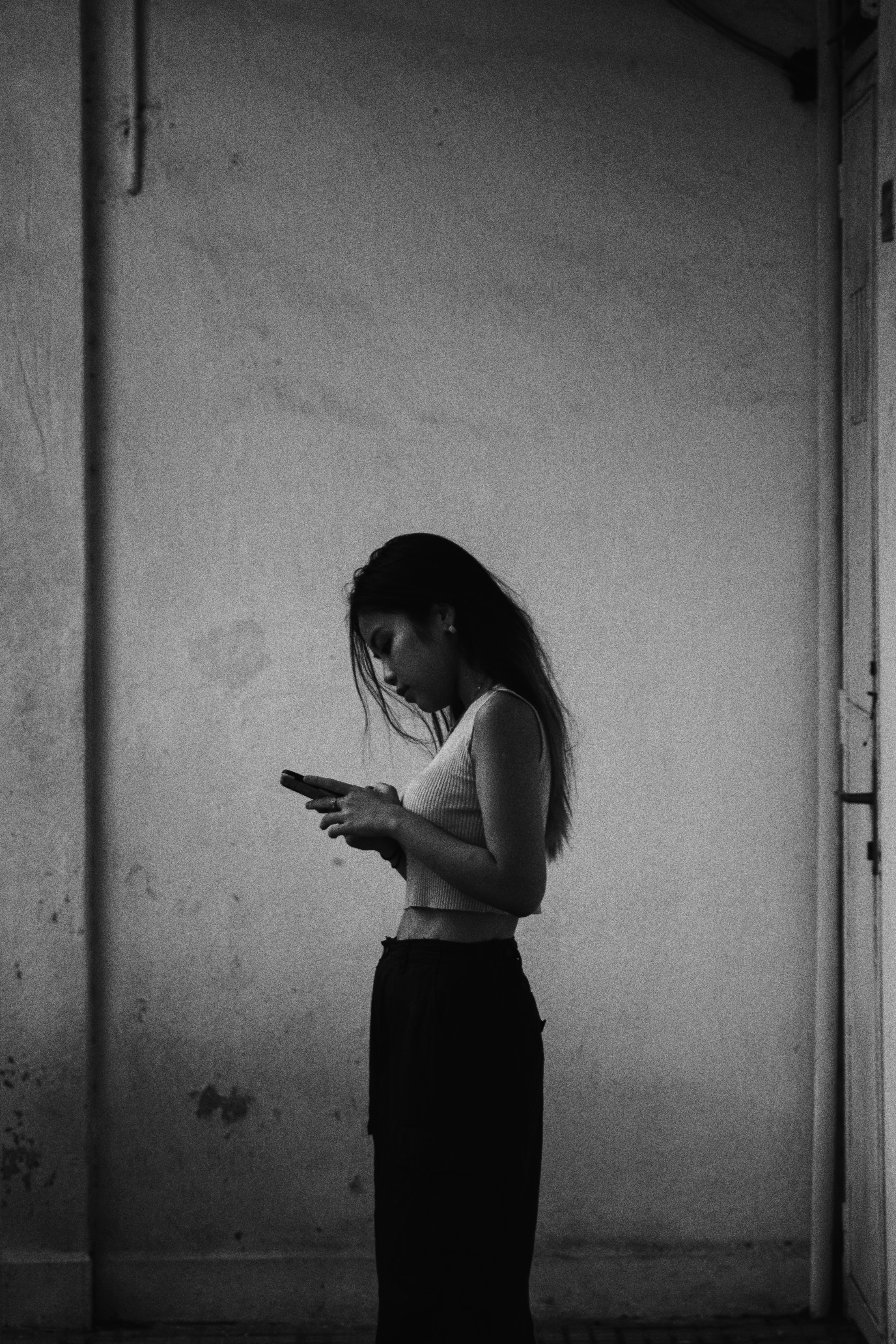 woman in black spaghetti strap top and black skirt standing in front of white wall